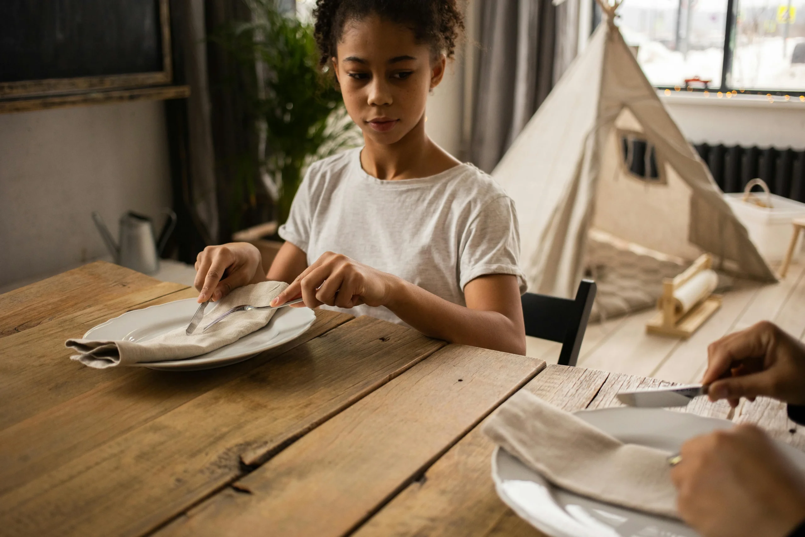 a girl at a table showing manners.