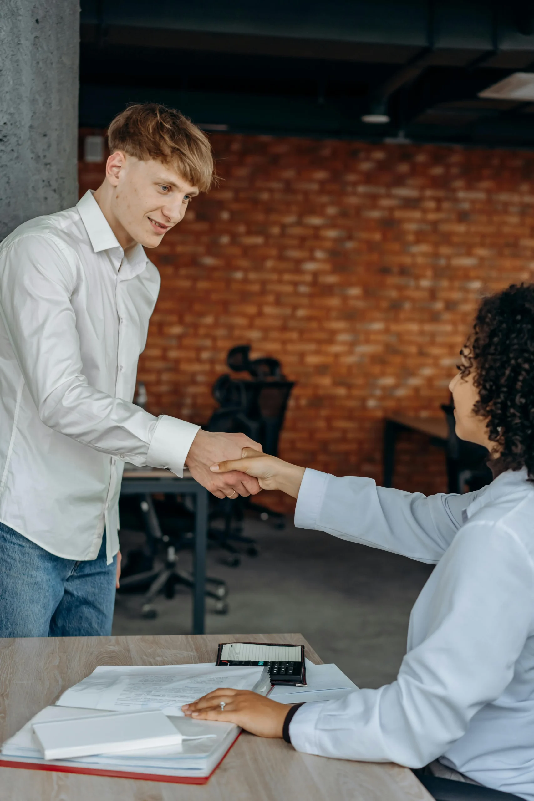 a young man shaking the hand of an older woman.